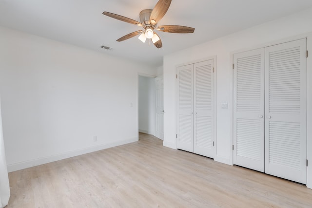 unfurnished bedroom with multiple closets, ceiling fan, and light hardwood / wood-style floors