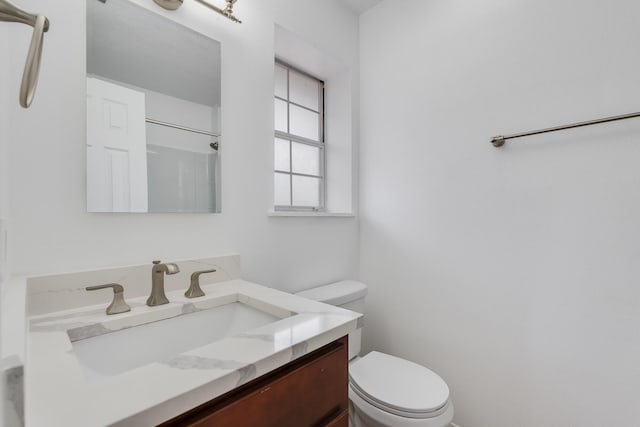 bathroom with vanity, toilet, and a shower