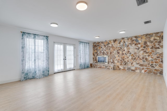 unfurnished living room with a fireplace, light hardwood / wood-style floors, and french doors