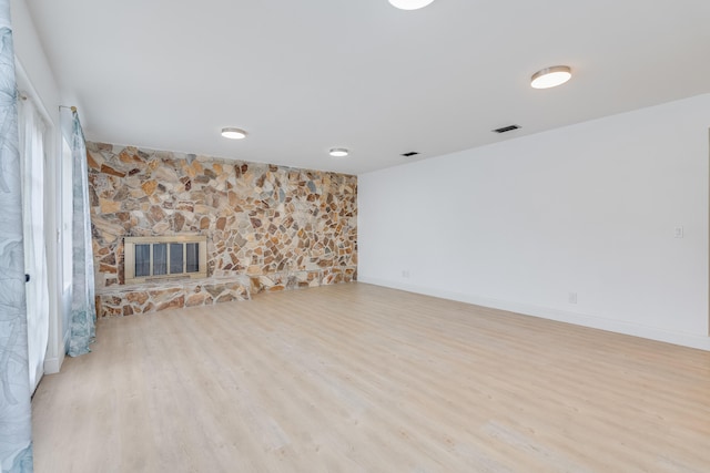 unfurnished living room featuring light hardwood / wood-style flooring and a stone fireplace