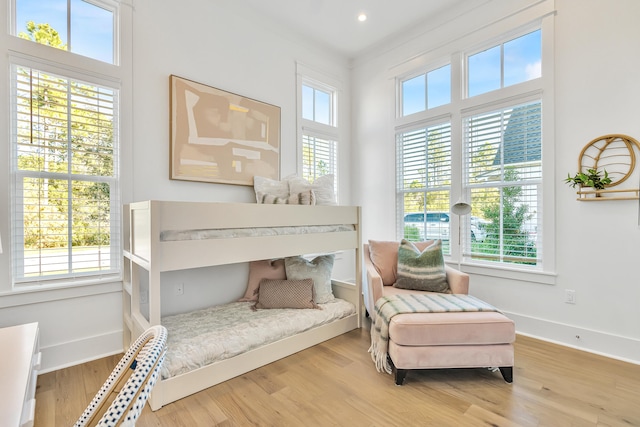 bedroom featuring hardwood / wood-style floors, crown molding, and multiple windows