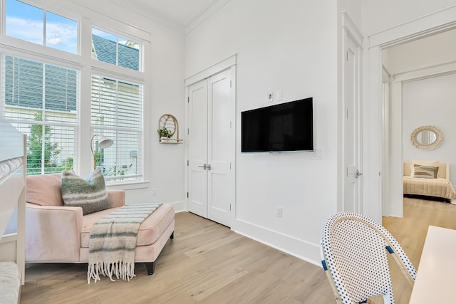 living area with light wood-type flooring, crown molding, and a healthy amount of sunlight