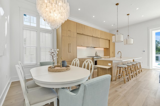 dining area with sink, light hardwood / wood-style flooring, a notable chandelier, and ornamental molding