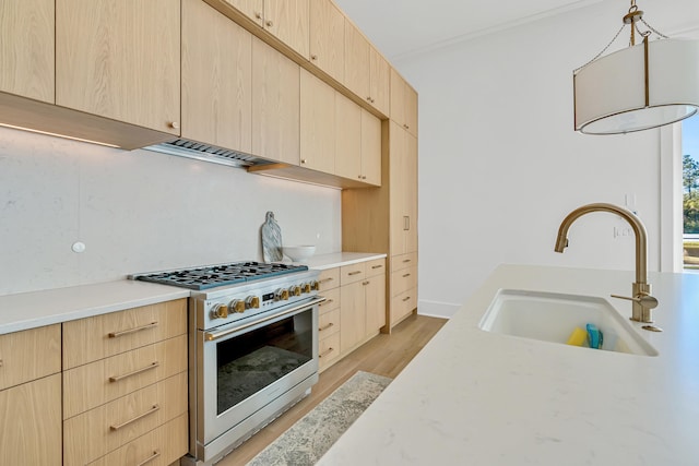 kitchen featuring stainless steel range, pendant lighting, light brown cabinets, and sink