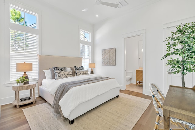 bedroom featuring hardwood / wood-style floors, ensuite bath, and multiple windows