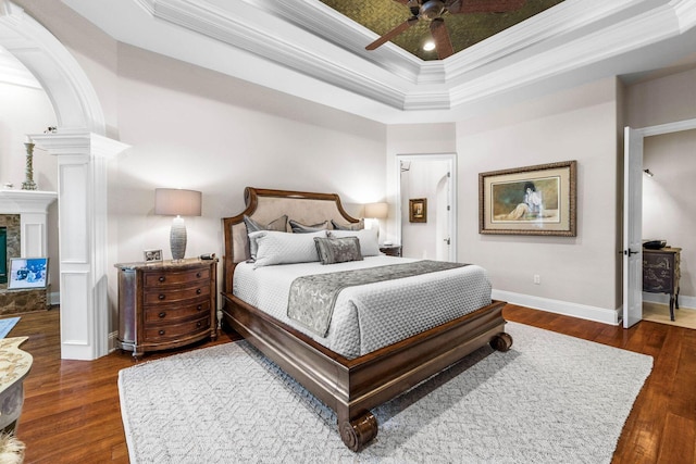 bedroom with ceiling fan, dark wood-type flooring, and a tray ceiling