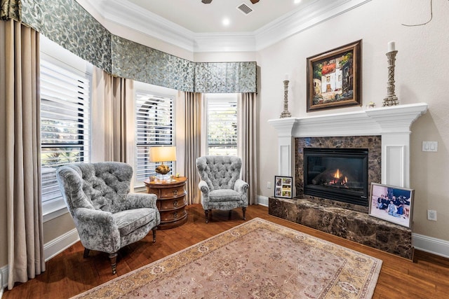 living area with a high end fireplace, hardwood / wood-style floors, plenty of natural light, and crown molding