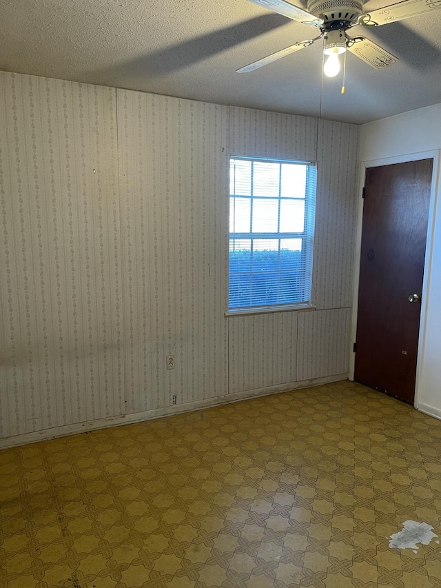 unfurnished room with ceiling fan and a textured ceiling