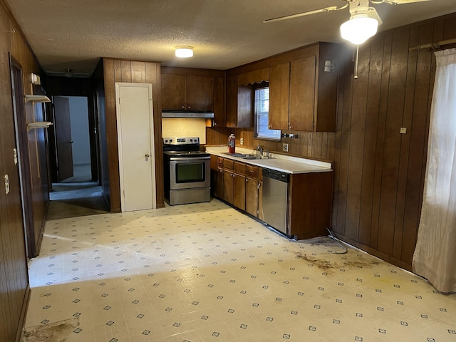 kitchen featuring wooden walls, a textured ceiling, and appliances with stainless steel finishes