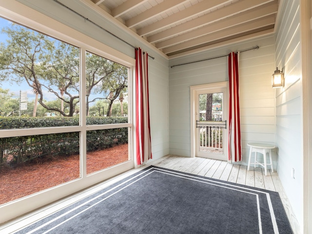 unfurnished sunroom featuring beam ceiling