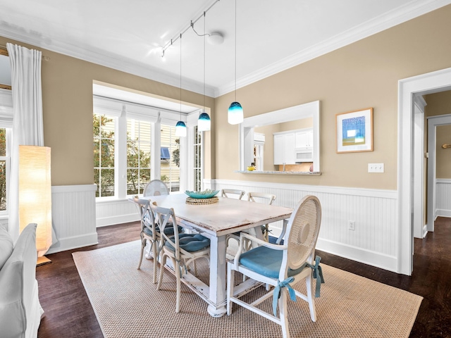 dining area with track lighting, crown molding, and dark wood-type flooring