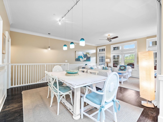 dining space featuring ceiling fan, rail lighting, dark wood-type flooring, and ornamental molding