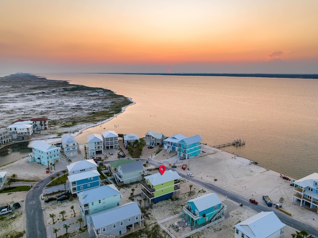 aerial view at dusk with a water view and a beach view