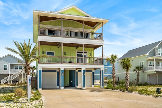 raised beach house featuring a garage and a balcony