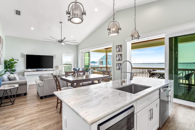 kitchen featuring white cabinetry, stainless steel appliances, sink, a kitchen island with sink, and a water view