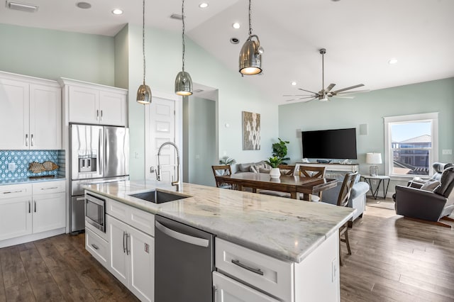 kitchen with appliances with stainless steel finishes, an island with sink, white cabinets, and sink