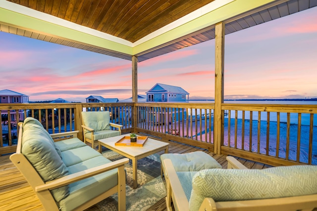 deck at dusk with an outdoor living space and a water view