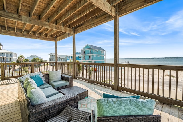 wooden terrace featuring a water view, an outdoor hangout area, and a view of the beach