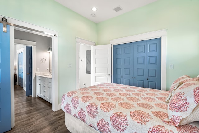 bedroom with ensuite bathroom, a closet, and dark wood-type flooring