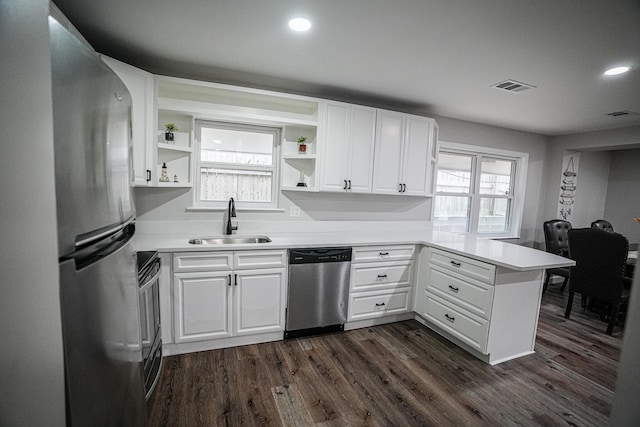 kitchen with kitchen peninsula, sink, white cabinets, and appliances with stainless steel finishes