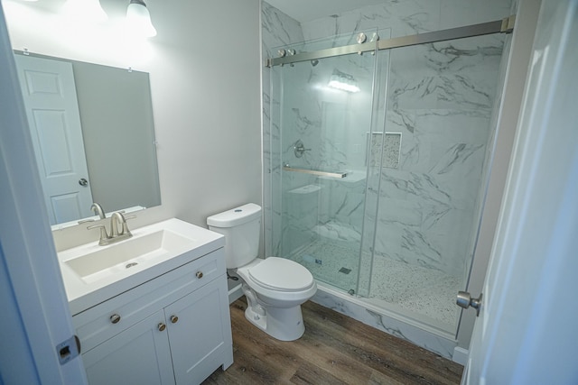 bathroom with hardwood / wood-style floors, vanity, toilet, and a shower with door