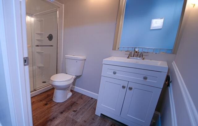 bathroom featuring hardwood / wood-style flooring, vanity, toilet, and walk in shower