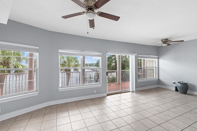 empty room with a wealth of natural light, light tile patterned flooring, a textured ceiling, and ceiling fan