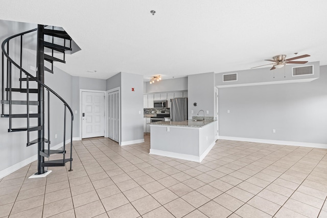 kitchen featuring ceiling fan, light stone counters, kitchen peninsula, white cabinets, and appliances with stainless steel finishes