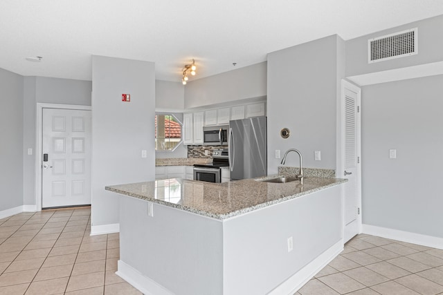 kitchen featuring sink, light tile patterned floors, kitchen peninsula, white cabinets, and appliances with stainless steel finishes