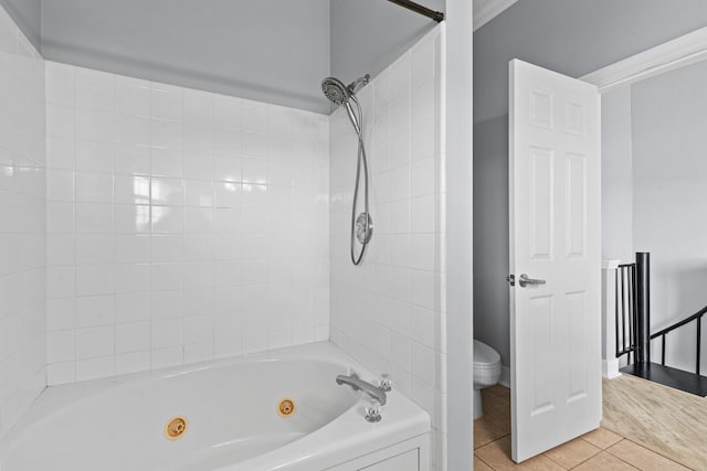 bathroom featuring tile patterned flooring, washtub / shower combination, and toilet