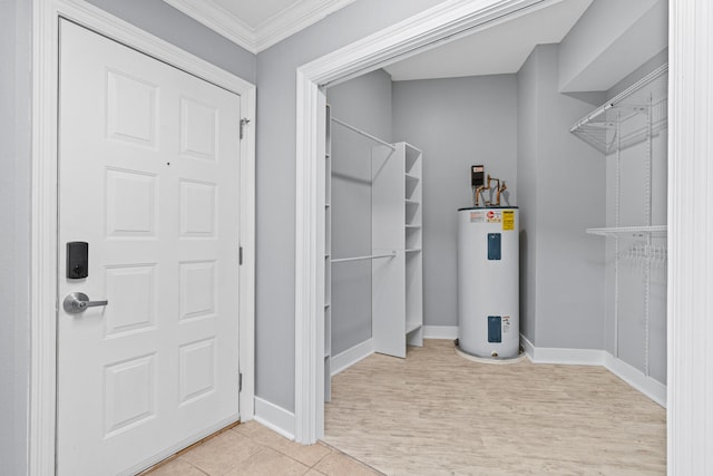 bathroom with electric water heater, crown molding, and tile patterned flooring