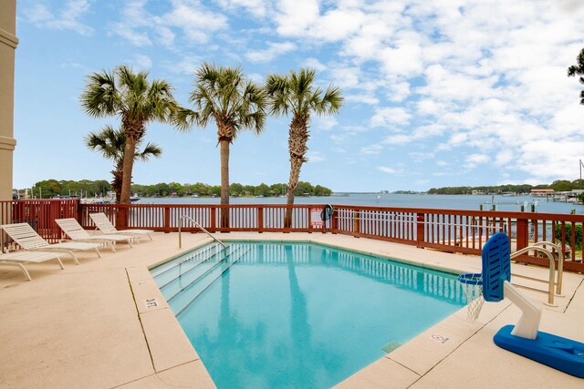 view of swimming pool featuring a patio area and a water view