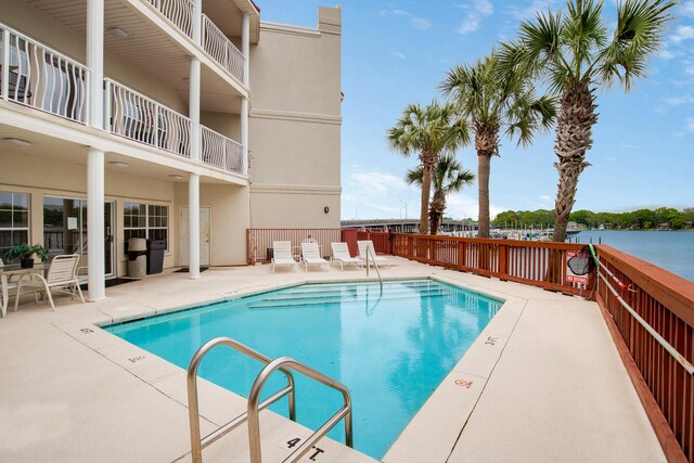 view of pool featuring a water view and a patio