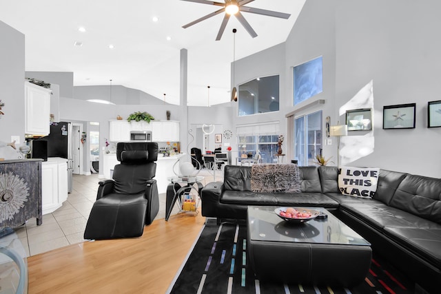 living room with light hardwood / wood-style flooring, high vaulted ceiling, and ceiling fan