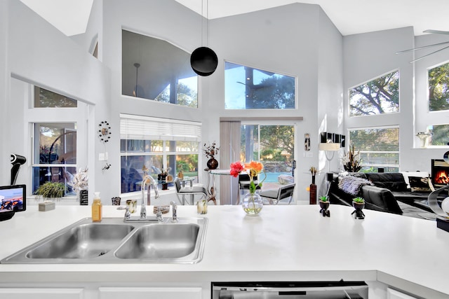 kitchen featuring dishwasher, a towering ceiling, white cabinetry, and sink