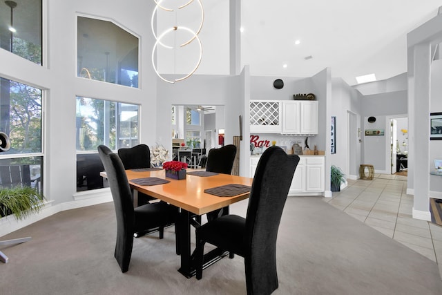 dining room featuring ceiling fan, light tile patterned flooring, and a towering ceiling