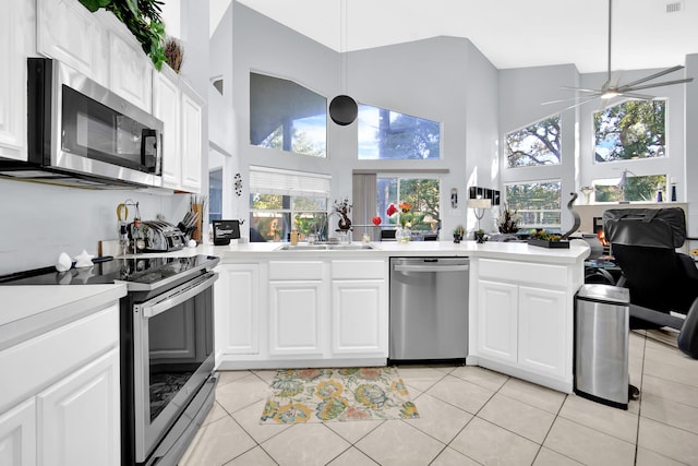 kitchen featuring white cabinetry, sink, stainless steel appliances, a towering ceiling, and light tile patterned flooring