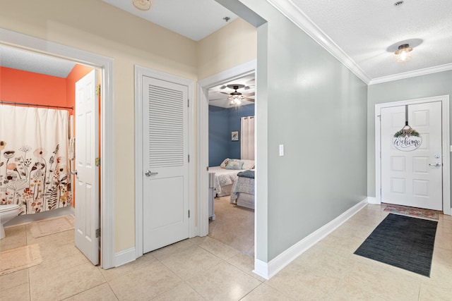 foyer entrance with ceiling fan, light tile patterned floors, a textured ceiling, and ornamental molding