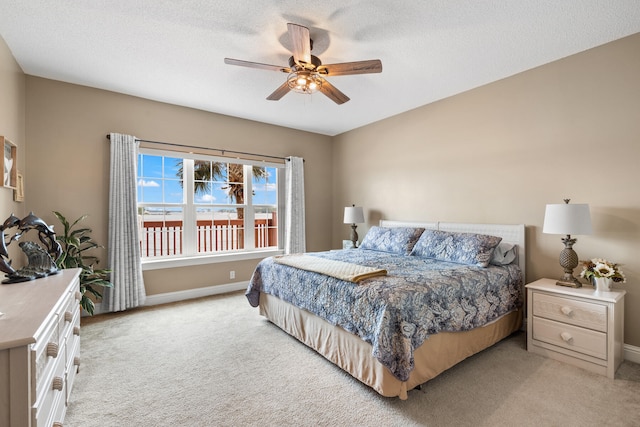 carpeted bedroom with ceiling fan and a textured ceiling