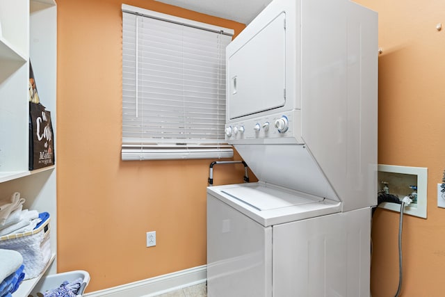 clothes washing area featuring stacked washing maching and dryer