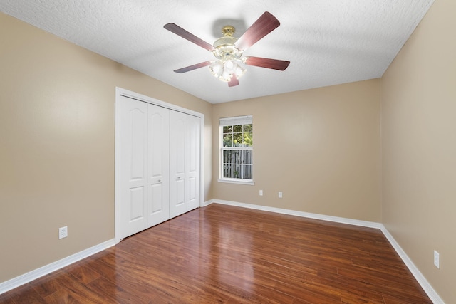 unfurnished bedroom featuring a closet, a textured ceiling, dark hardwood / wood-style floors, and ceiling fan