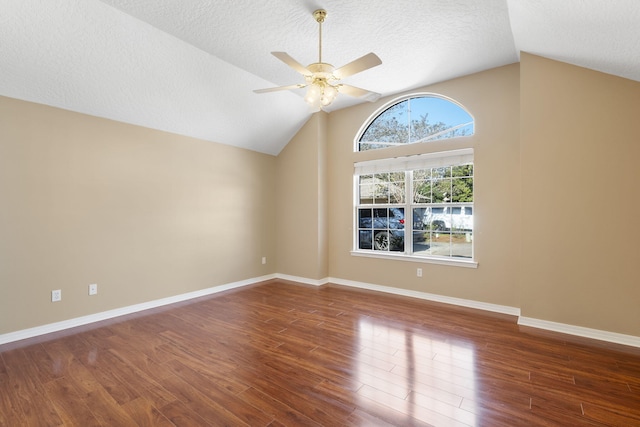 interior space with a textured ceiling, dark wood-type flooring, and vaulted ceiling