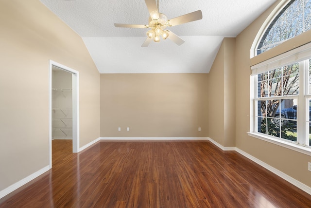 interior space with lofted ceiling, dark hardwood / wood-style flooring, ceiling fan, and a textured ceiling