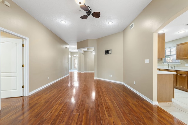 unfurnished living room with ceiling fan, light hardwood / wood-style floors, and a textured ceiling