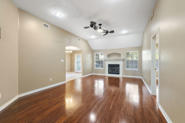 unfurnished living room featuring ceiling fan with notable chandelier, a textured ceiling, hardwood / wood-style flooring, and lofted ceiling