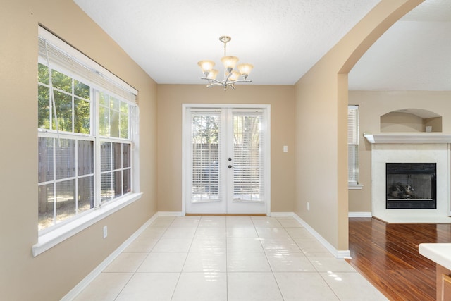 doorway to outside featuring a chandelier, french doors, a textured ceiling, and light hardwood / wood-style flooring