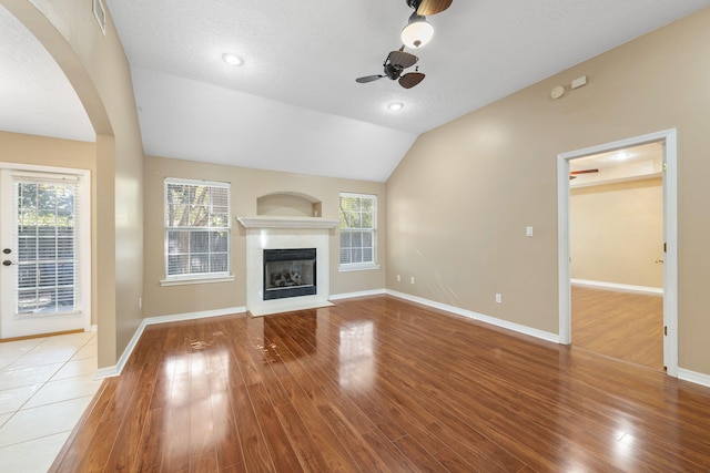 unfurnished living room featuring lofted ceiling, ceiling fan, wood-type flooring, and a textured ceiling