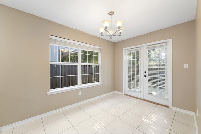 unfurnished dining area with plenty of natural light, light tile patterned floors, a chandelier, and a textured ceiling