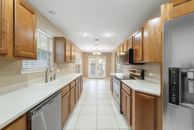 kitchen featuring appliances with stainless steel finishes, a textured ceiling, sink, light tile patterned floors, and a chandelier