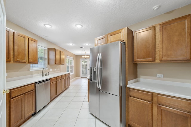 kitchen with sink, light tile patterned floors, a textured ceiling, and appliances with stainless steel finishes